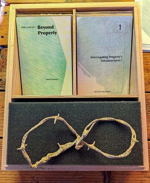 A wooden box containing colorful printed booklets and a paper-covered barbed wire object.