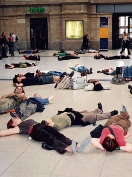 People lay on their backs in a large lobby space.